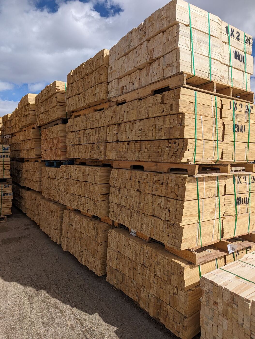 Pallets of milled wood stakes stacked in the yard.